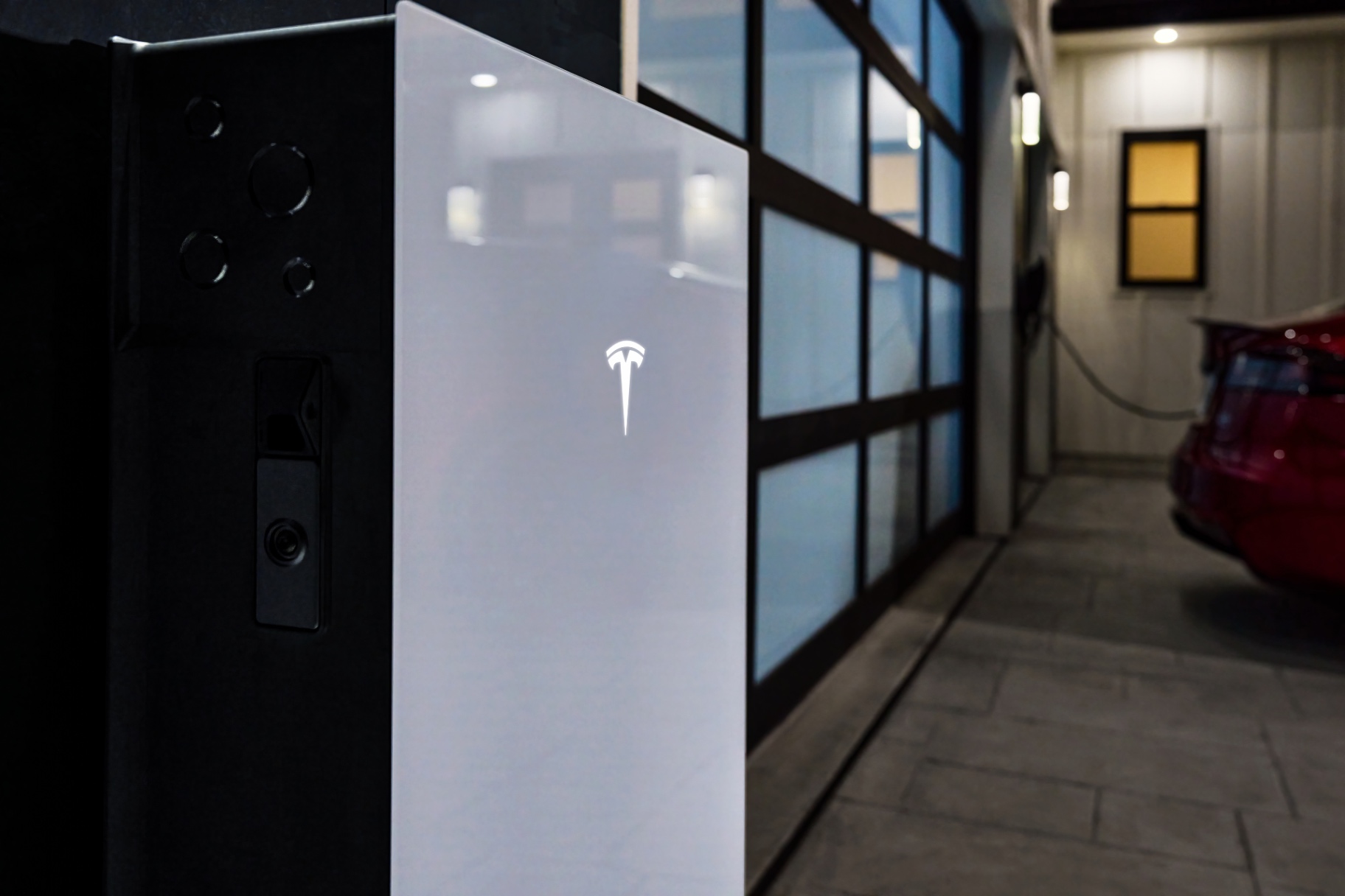 Tesla Powerwall 3P thuisbatterij naast een geparkeerde Tesla in de garage