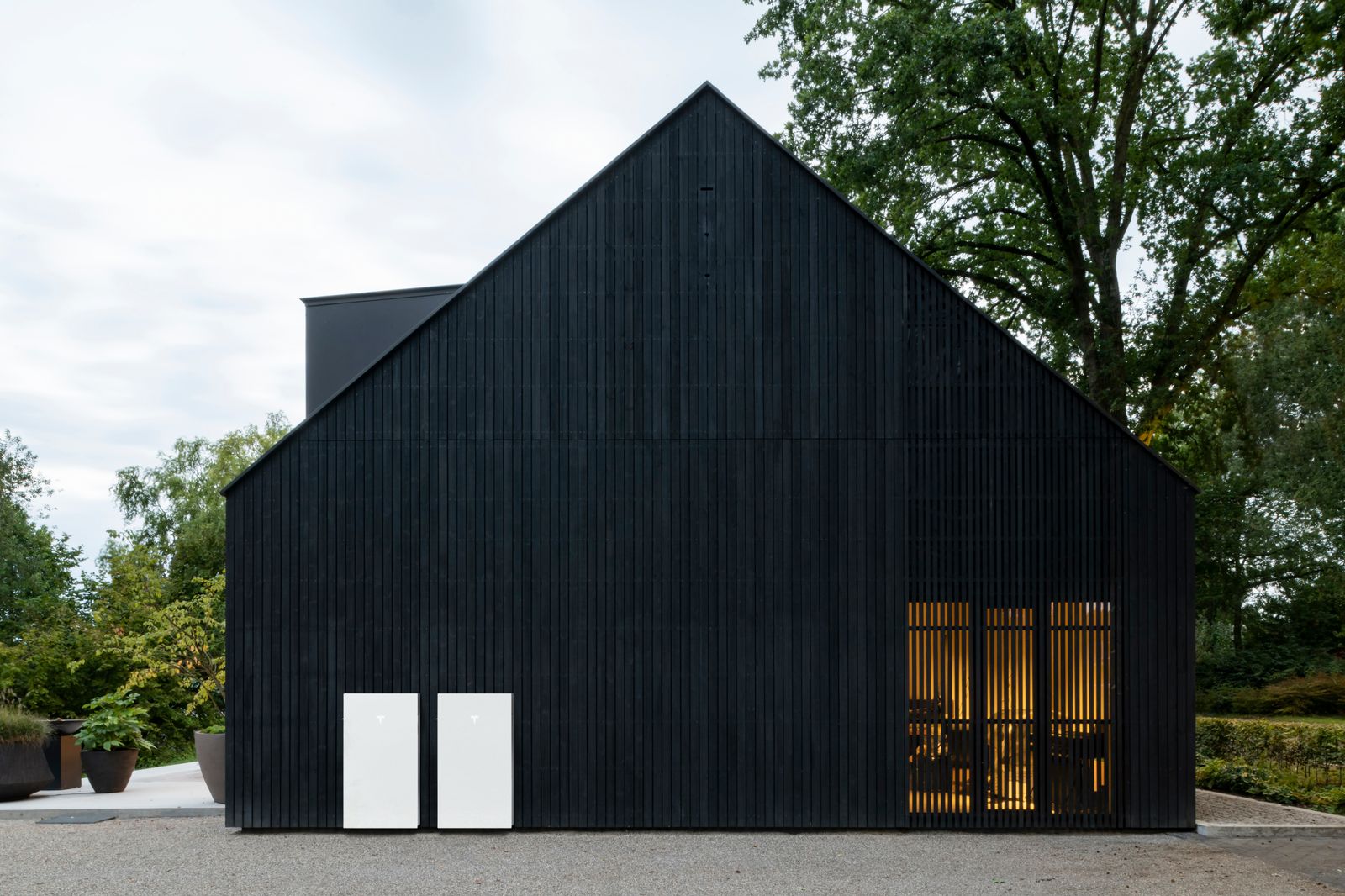 Twee Tesla Powerwall 3-units aan de houten gevel van een woning zonder zonnepanelen