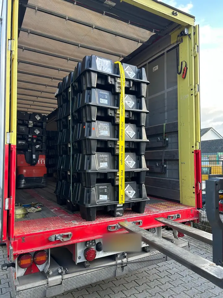 Pallets met Tesla Powerwalls in de geopende oplegger van de vrachtwagen, met de vorken van de heftruck klaar om uit te laden